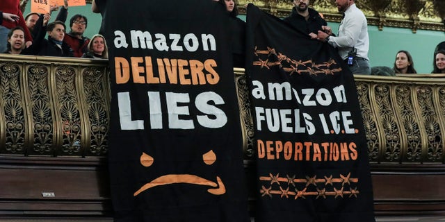 Protestors unfurled anti-Amazon banners from the balcony of a hearing room during a New York City Council Finance Committee hearing at New York City Hall, January 30, 2019. (Photo by Drew Angerer/Getty Images)