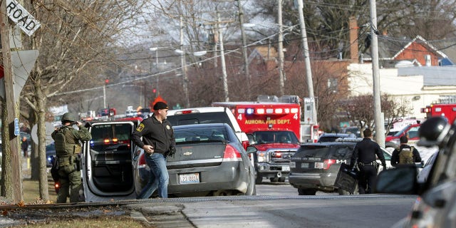 Law enforcement personnel gather near the scene of a shooting at an industrial park in Aurora, Ill., on Friday.
