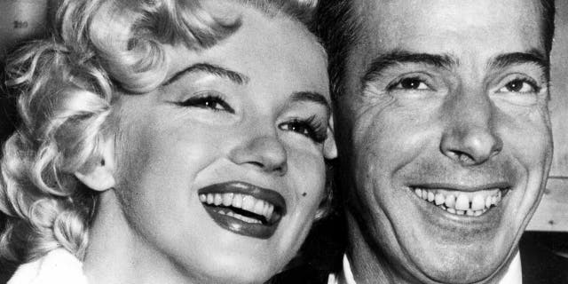 FILE - In this Jan. 14, 1954 file photo, New York Yankees' Joe DiMaggio, right, poses with actress Marilyn Monroe, as they wait for their marriage ceremony in San Francisco. The black dress that a distraught Marilyn Monroe wore to a 1954 press conference announcing her separation from baseball legend Joe DiMaggio is going up for auction.