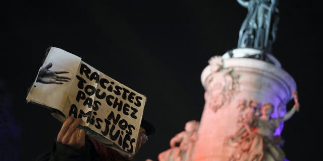 A man holds a poster reading "Racists, Don't Touch to Our Jewish Friends" during a gathering decrying anti-Semitism at Place de la Republique in Paris, Monday, Feb. 18, 2019 amid an upsurge in anti-Semitism in France.