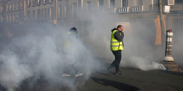 Yellow vest protesters walk through tear gas during a demonstration Saturday, Feb.16, 2019 in Paris.