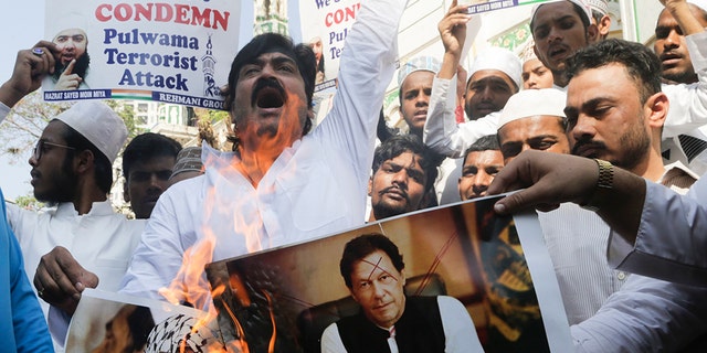 Indian Muslims burn posters of Pakistani prime minister Imran Khan, center, and Jaish-e-Mohammed leader Masood Azhar, during a protest against Thursday's attack on a paramilitary convoy in Kashmir that killed at least 40, in Mumbai, India, Friday.