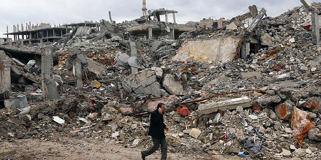 A man walks past damaged buildings in the northern Syrian town of Kobani January 30, 2015.