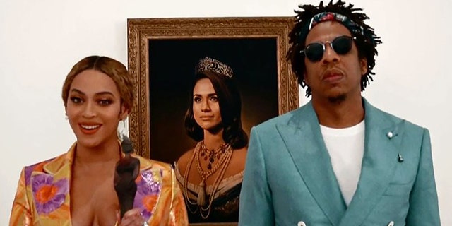 Beyonce and Jay-Z infront of a portrait of Meghan Markle