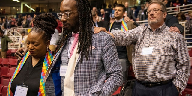 Adama Brown-Hathasway, left, The Rev. Dr. Jay Williams, both from Boston, and Ric Holladay of Kentucky join in prayer during the 2019 Special Session of the General Conference of The United Methodist Church in St. Louis