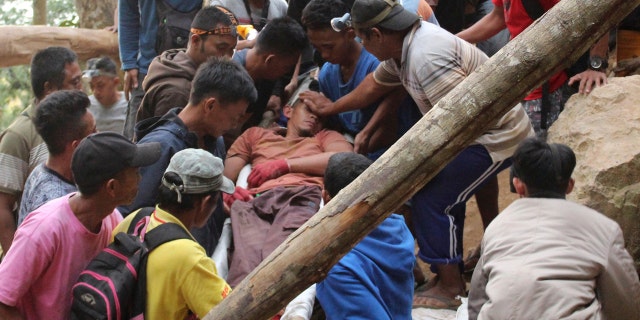 Rescuers carry a survivor from inside a collapsed mine in Bolaang Mongondow, North Sulawesi, Indonesia, Wednesday, Feb. 27, 2019.