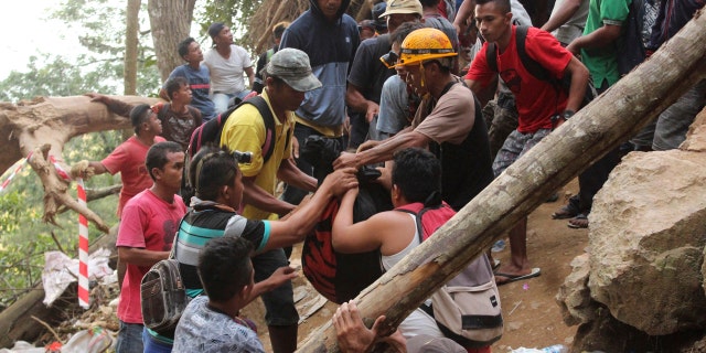 Rescuers carry the body of a victim of a collapsed mine in Bolaang Mongondow, North Sulawesi, Indonesia, Wednesday, Feb. 27, 2019.