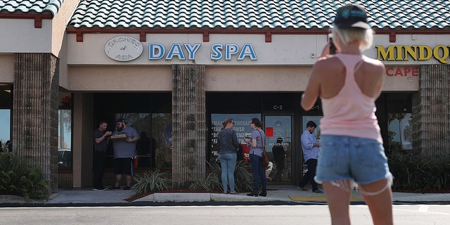 People gather in front of the Orchids of Asia Day Spa in Jupiter, Florida. (Photo by Joe Raedle/Getty Images)