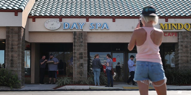 People gather in front of the Orchids of Asia Day Spa in Jupiter, Florida. (Photo by Joe Raedle/Getty Images)