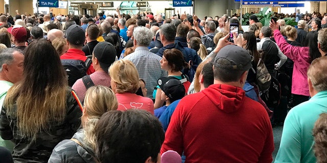 People wait to get through security at the Orlando International Airport following a security incident on Saturday, after flights were grounded following an apparent suicide. (Jonathan Hayward/The Canadian Press via AP)