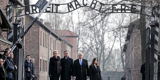 United States Vice President Mike Pence and his wife Karen Pence, right, stand with Poland's President Andrzej Duda and his wife Agata Kornhauser-Duda, left, under the gate during their visit at the Nazi concentration camp Auschwitz-Birkenau in Oswiecim, Poland, Friday, Feb. 15, 2019. They stand under the infamous "Arbeit Macht Frei" sign
