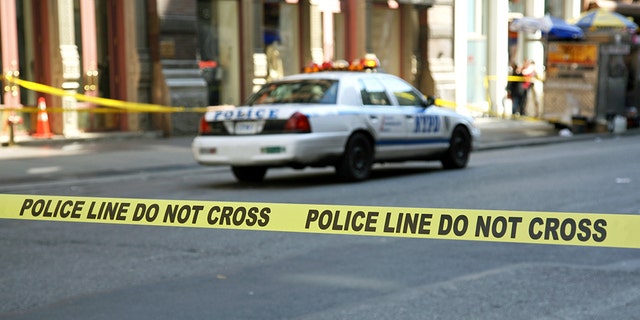 Police tape hangs across a street in front of a building, New York City, New York, USA.