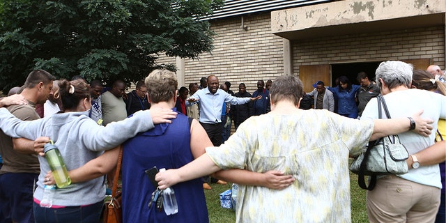 A pastor leads people in prayer at the site of a walkway collapse at the Driehoek High School in Vanderbijlpark, South Africa, Friday, Feb. 1, 2019. At least 3 students were killed and scores injured at the school near Johannesburg, a South African official said.