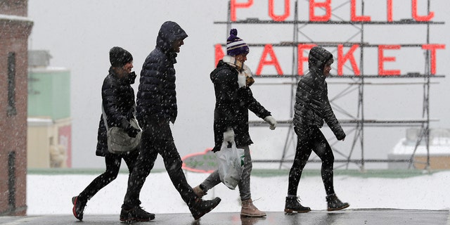 Пешеходы гуляют возле рынка Пайк-плейс, так как в понедельник, 11 февраля 2019 года, в центре Сиэтла выпадает снег. Школы были закрыты через штат Вашингтон, так как зимние снежные бури продолжали избивать северо-запад. В феврале район метро Сиэтла уже пострадал от трех метелей, что делает его самым снежным месяцем в Сиэтле за последние 30 лет. (AP Photo / Ted S. Warren)