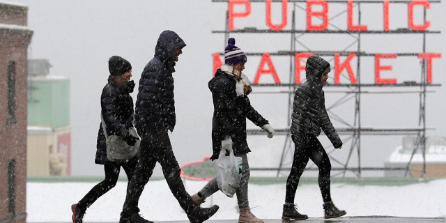 Pedestrians walk near Pike Place Market as snow falls Monday, Feb. 11, 2019, in downtown Seattle. Schools were closed across Washington state as winter snowstorms continued pummeling the Northwest. Seattle's metro area has already been hit by three snowstorms in February, making it the snowiest month in Seattle in more than 30 years. (AP Photo/Ted S. Warren)