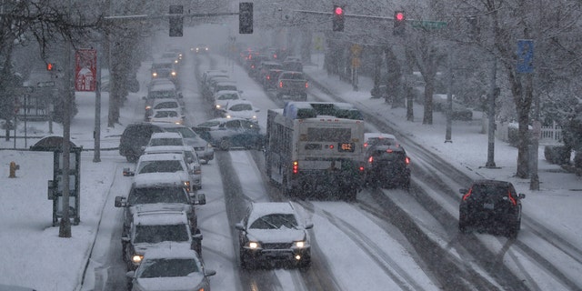   Cars and a bus travel in the snow on Capitol Way on Friday, February 8, 2019 in Olympia, Washington. 