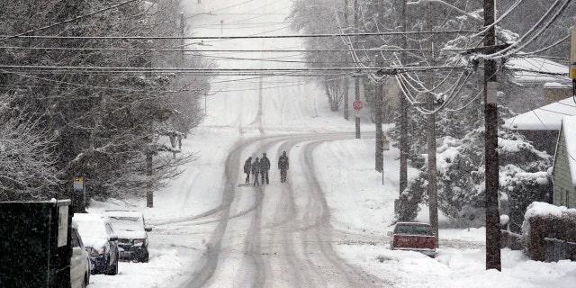 Pedestrians cross a deserted street as heavy snow falls Monday, Feb. 11, 2019, in Seattle.