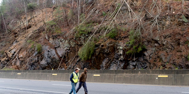 Workers walk past the landslide scene of the I-40 to the east in Clyde, North Carolina, near the borders of Tennessee and North Carolina. on Saturday, February 23, 2019.