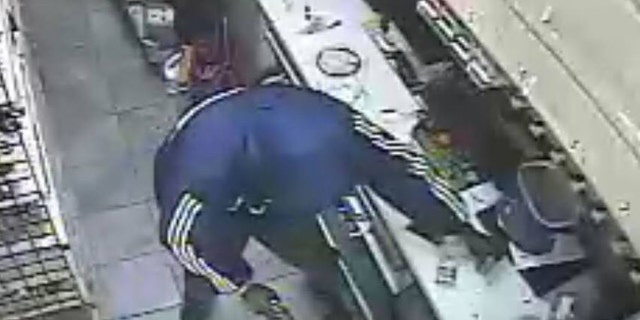 A security camera image shows one of the two suspects the moment after the clerk was killed.