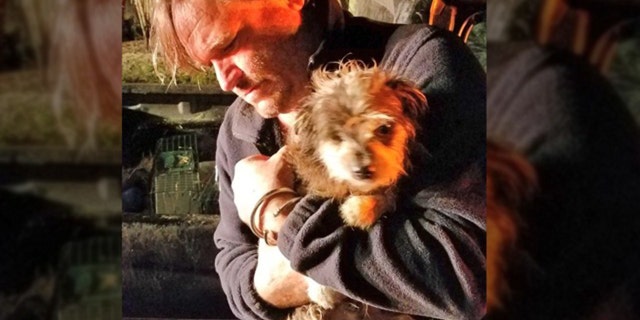 Second Chance Wildlife Sanctuary's Jim Bronzo cradles dog named Yoshi he rescured from fire.