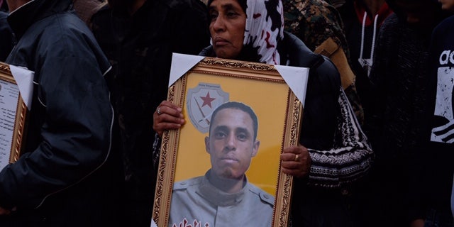 A grieving mother holds a portrait of her son who was killed fighting ISIS in Deir-ez-Zor in January 2019.