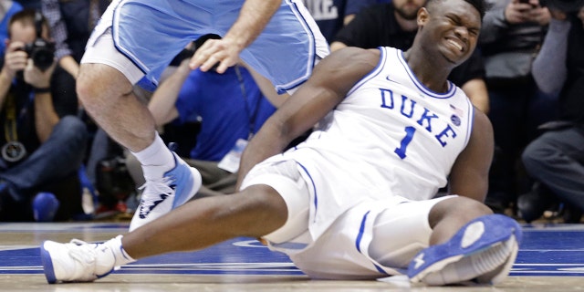 Duke's Zion Williamson (1) falls to the floor with an injury while chasing the ball with North Carolina's Luke Maye (32) during the first half of an NCAA college basketball game in Durham, N.C., Wednesday, Feb. 20, 2019.