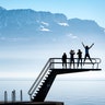 Kids enjoy the sunny warm weather on a diving platform on the shore of the Lake Geneva in front of the Swiss and French Alps in Lutry, Switzerland, Feb. 16, 2019. 