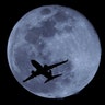 A passenger jet is silhouetted against the rising full moon as it takes off from Sky Harbor airport in Phoenix, Ariz., Feb. 19, 2019. 