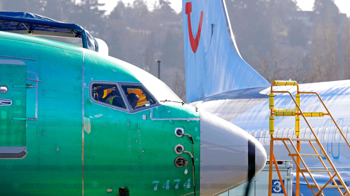 In this March 13, 2019, file photo people work in the flight deck of a Boeing 737 MAX 8 airplane being built for TUI Group parked next to another MAX 8 also designated for TUI at Boeing Co.'s Renton Assembly Plant in Renton, Wash.
