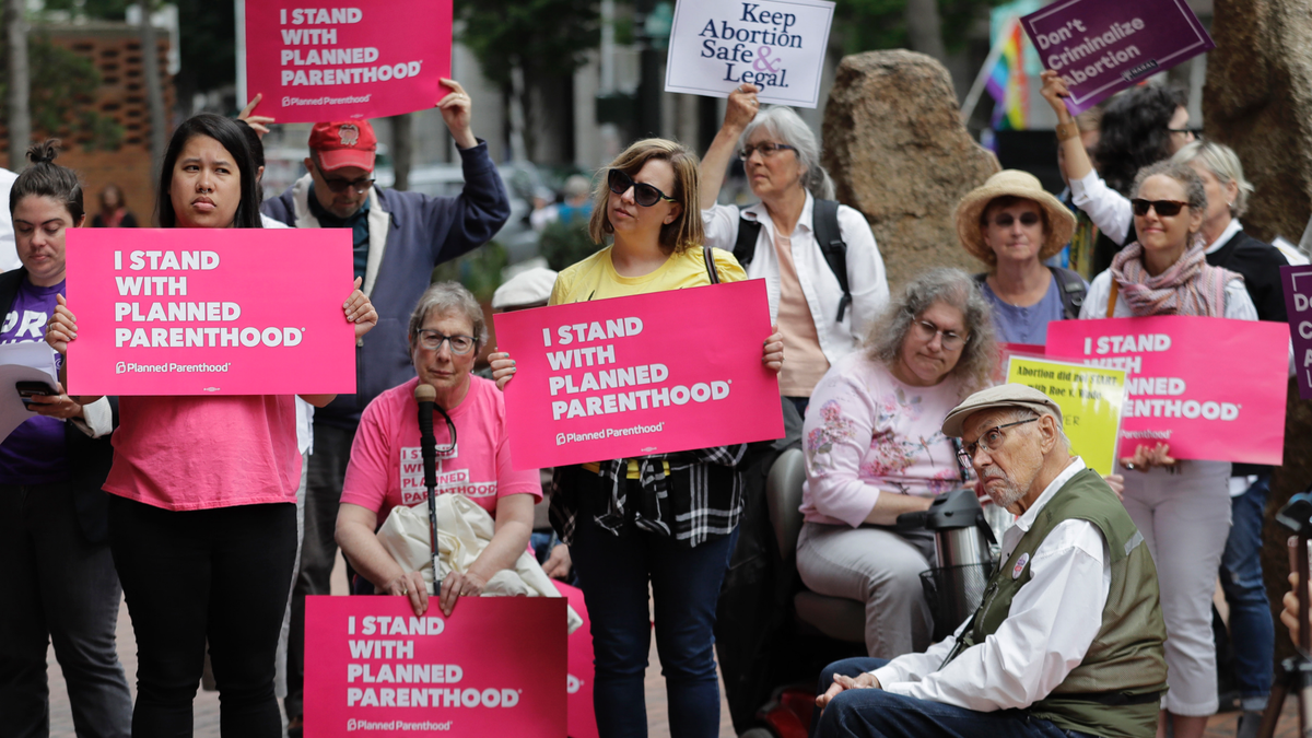 In this July 10, 2018, photo, protesters hold signs supporting Planned Parenthood in Seattle. (AP Photo/Ted S. Warren, File)
