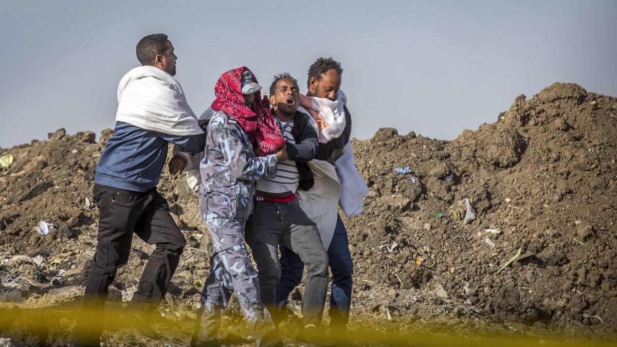 A grieving relative who lost his wife in the crash is helped by a member of security forces and others at the scene where the Ethiopian Airlines Boeing 737 Max 8 crashed shortly after takeoff on Sunday.