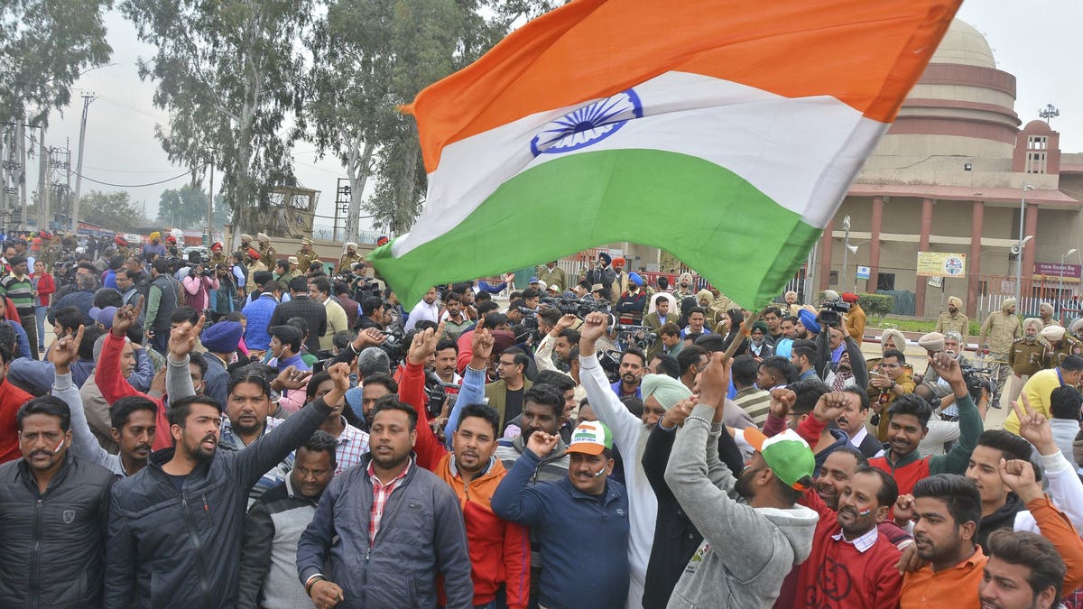 An Indian waves national flag as others shout slogans ahead of welcoming back their pilot from Pakistan.