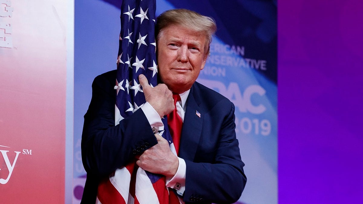 President Donald Trump hugs the American flag as he arrives to speak at Conservative Political Action Conference, CPAC 2019, in Oxon Hill, Md., Saturday, March 2, 2019. (Associated Press)