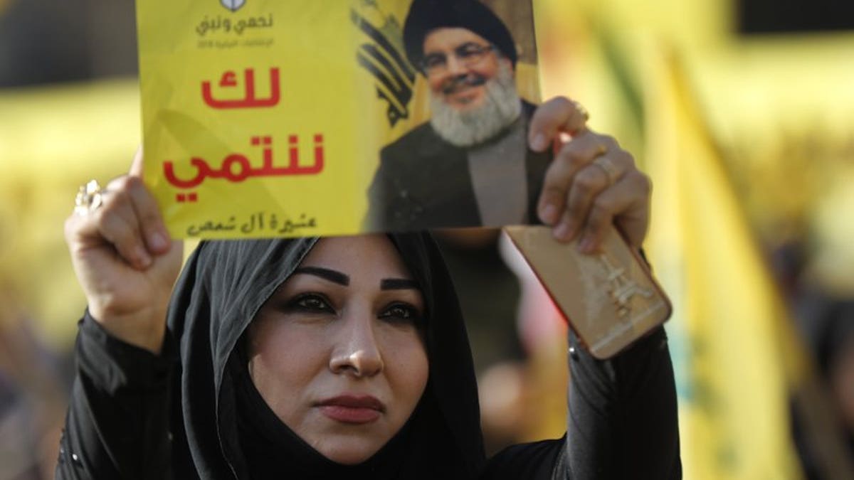 In this April 13, 2018, file photo, a supporter of Hezbollah leader Sayyed Hassan Nasrallah holds up his portrait with Arabic words that read: "We belong with you," during an election campaign speech in a southern suburb of Beirut, Lebanon.
