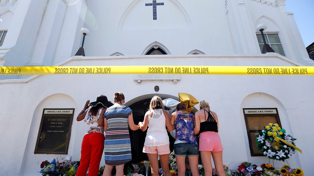 In this June 18, 2015, file photo, a group of women pray together at a makeshift memorial on the sidewalk in front of the Emanuel AME Church, in Charleston, S.C. Dylann Roof, shot a killed nine people while they were in a bible study at the church. A shooting at a Tennessee church on Sunday, Sept. 24, 2017, has demonstrated again that deadly violence at U.S. houses of worship is not rare. (AP Photo/Stephen B. Morton, File)