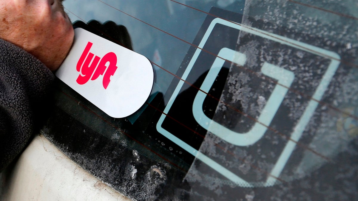 A Lyft logo is installed on a Lyft driver's car next to an Uber sticker in Pittsburgh, Jan. 31, 2018. (Associated Press)