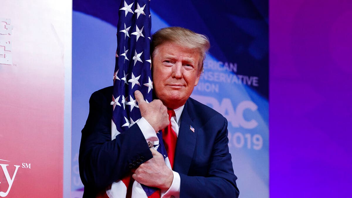 President Donald Trump hugs the American flag as he arrives to speak at Conservative Political Action Conference, CPAC 2019, in Oxon Hill, Maryland, Saturday, March 2, 2019.