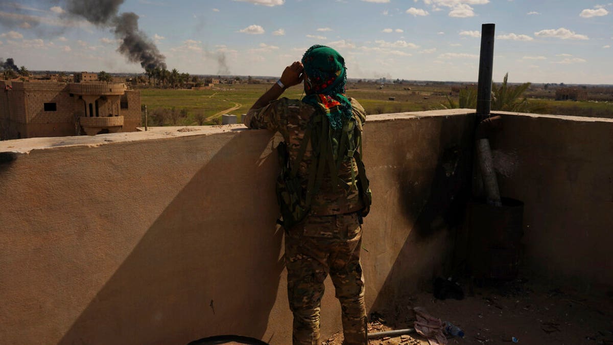 A U.S.-backed Syrian Democratic Forces (SDF) fighter watches black smoke billow from the last small piece of territory held by Islamic State militants as U.S. backed fighters pounded the area with artillery fire and occasional airstrikes in Baghouz, Syria, Sunday, March 3, 2019. (AP Photo/Andrea Rosa)