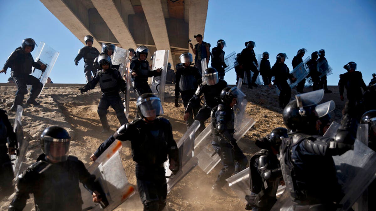 FILE - In this Nov. 25, 2018 file photo, Mexican police run as they try to keep migrants from getting past the Chaparral border crossing in Tijuana, Mexico, near San Ysidro, Calif. (AP Photo/Ramon Espinosa, File)