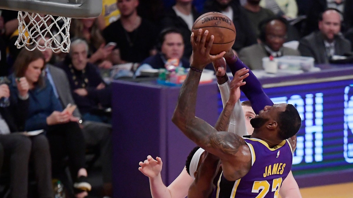 Los Angeles Lakers forward LeBron James, right, shoots and scores as Denver Nuggets forward Torrey Craig defends during the first half of an NBA basketball game Wednesday, March 6, 2019, in Los Angeles. (Associated Press)