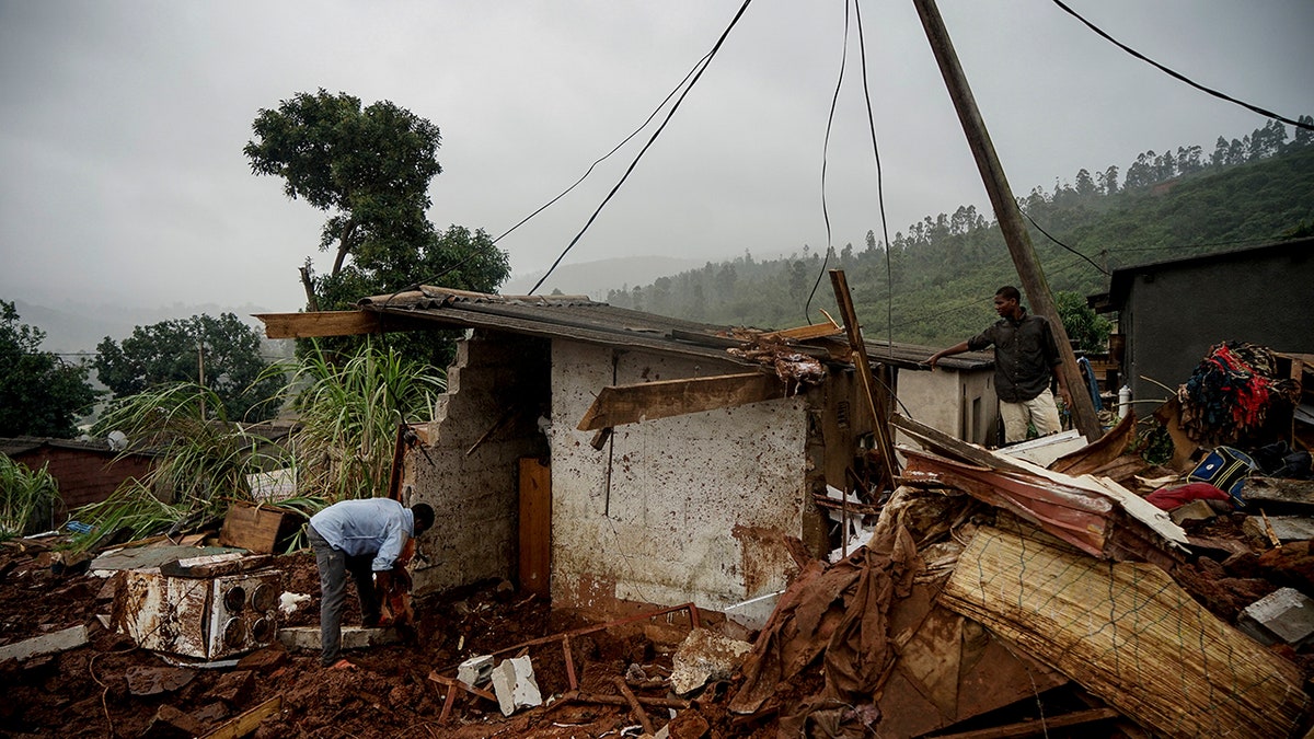 Men search to salvage what they can from a house which was damaged by Cyclone Idai in Chimanimani, Zimbabwe, Saturday, March 23, 2019 after Cyclone Idai caused floods that swept through Mozambique, Zimbabwe and Malawi. A second week has begun of efforts to find and help some tens of thousands of people in devastated parts of southern Africa, with some hundreds dead and an unknown number of people still missing.(AP Photo/KB Mpofu)