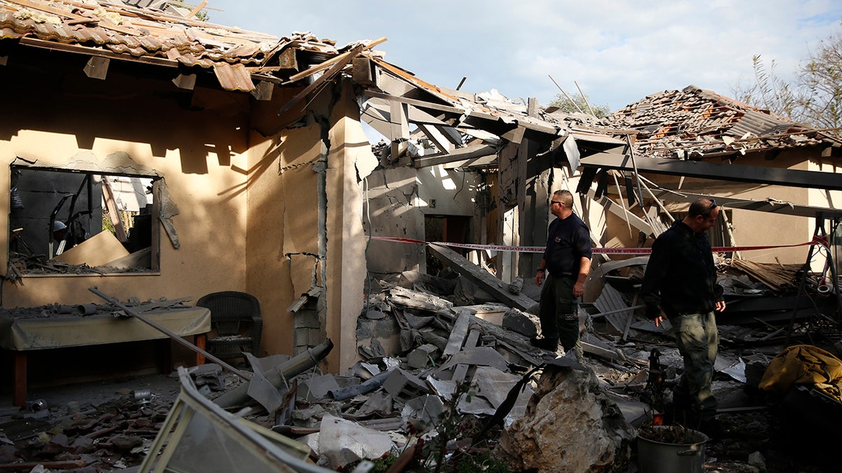 Police officers inspect the damage to a house hit by a rocket in Mishmeret, central Israel, Monday, March 25, 2019. An early morning rocket from the Gaza Strip struck a house in central Israel on Monday, wounding six people, including one moderately, an Israeli rescue service said, in an eruption of violence that could set off another round of violence shortly before the Israeli election. (AP Photo/Ariel Schalit)