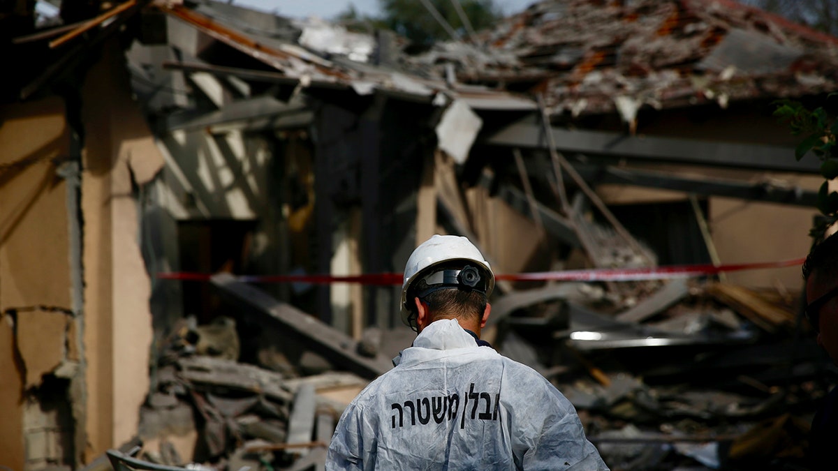 An Israeli police officer inspects the damage to a house hit by a rocket in Mishmeret, central Israel, Monday, March 25, 2019. An early morning rocket from the Gaza Strip struck a house in central Israel on Monday, wounding several people, including one moderately, an Israeli rescue service said, in an eruption of violence that could set off another round of violence shortly before the Israeli election. (AP Photo/Ariel Schalit)