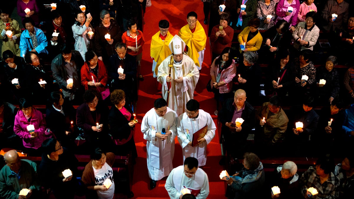 FILE - In this Saturday, March 31, 2018, file photo, Chinese Bishop Joseph Li Shan, center, walks down the aisle during a Holy Saturday Mass on the evening before Easter at the Cathedral of the Immaculate Conception, a government-sanctioned Catholic church in Beijing. (AP Photo/Mark Schiefelbein, File)