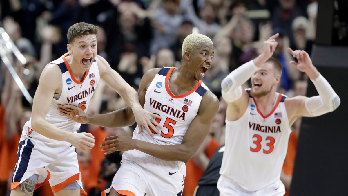 Virginia's Mamadi Diakite, center, reacts with teammates Kyle Guy and Jack Salt (33) after hitting a shot to send the game into overtime in the men's NCAA Tournament college basketball South Regional final game against Purdue, Saturday, March 30, 2019, in Louisville, Ky. (Associated Press)