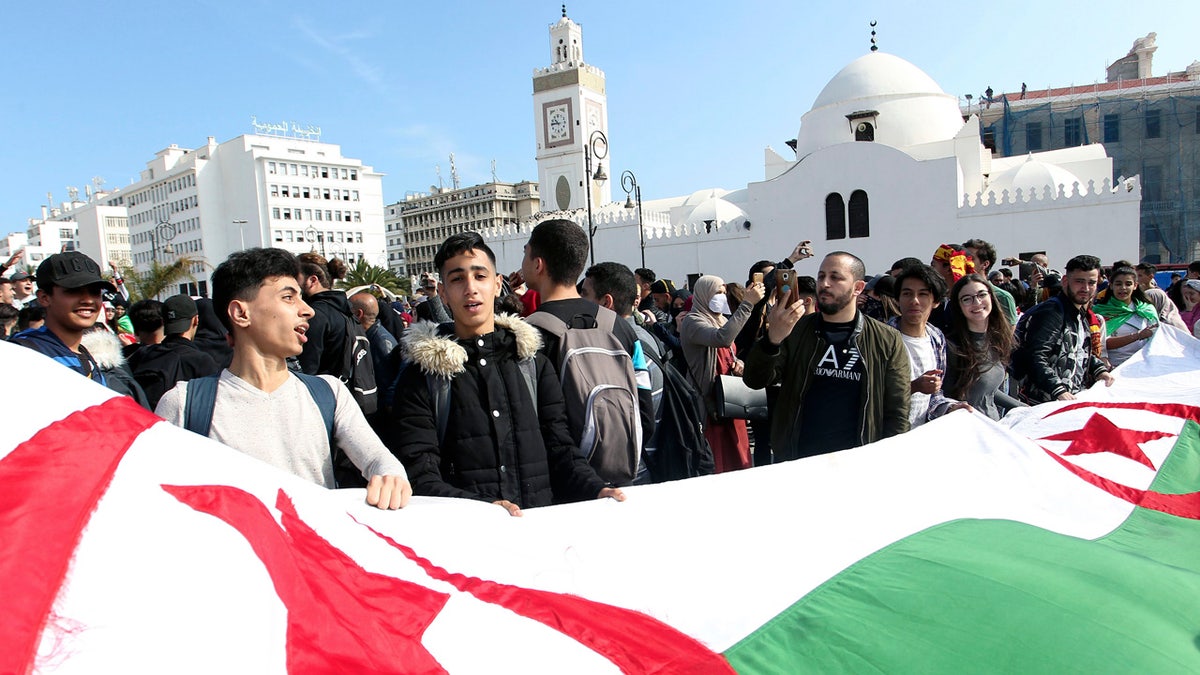 High school students marching with a huge national flag in central Algiers Sunday. (AP Photo/Anis Belghoul)