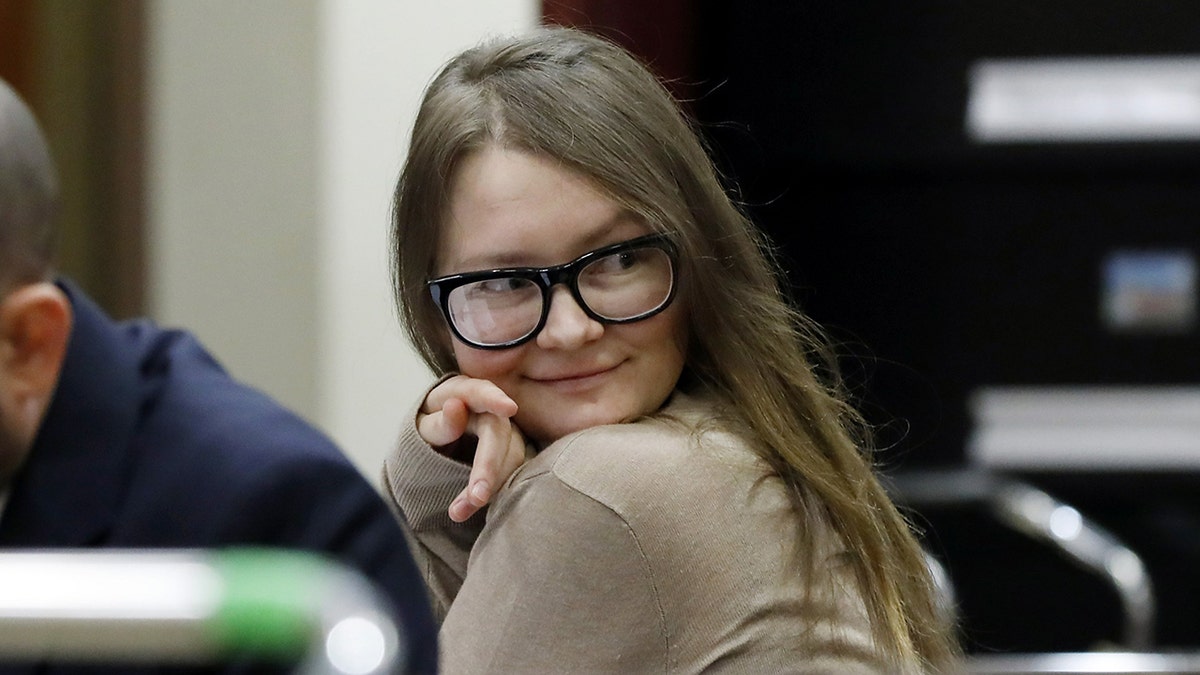 Anna Sorokin wearing her signature black framed glasses