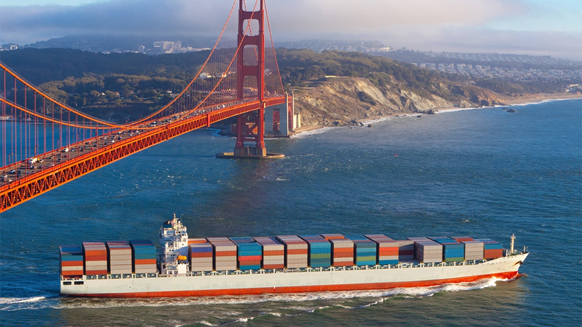 Full container cargo ship sailing out of San Francisco bay under the Golden gate bridge and heading out into the Pacific Ocean in the late afternoon