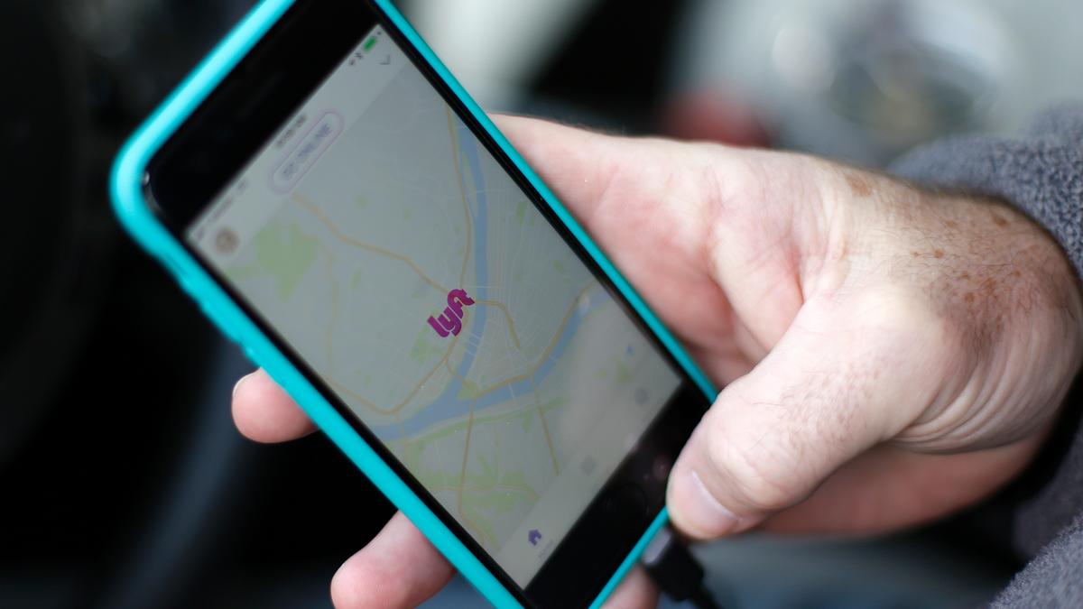 Person holds phone with Lyft app opened