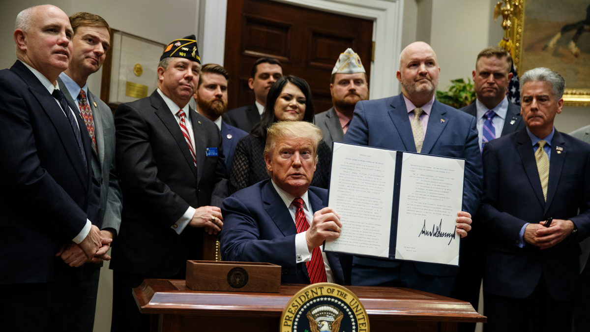 President Trump displays his signed executive order establishing a "National Roadmap to Empower Veterans and End Veteran Suicide" in March 2019. (AP Photo/ Evan Vucci)